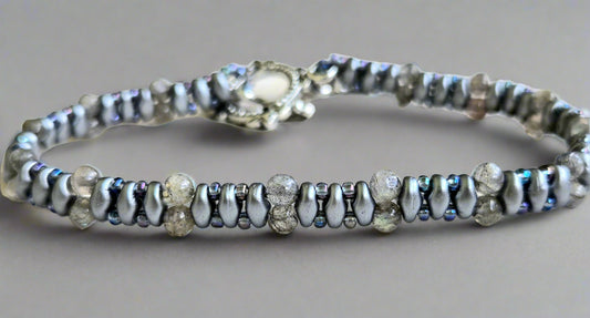 Silver bracelet with small beads on a light wooden surface