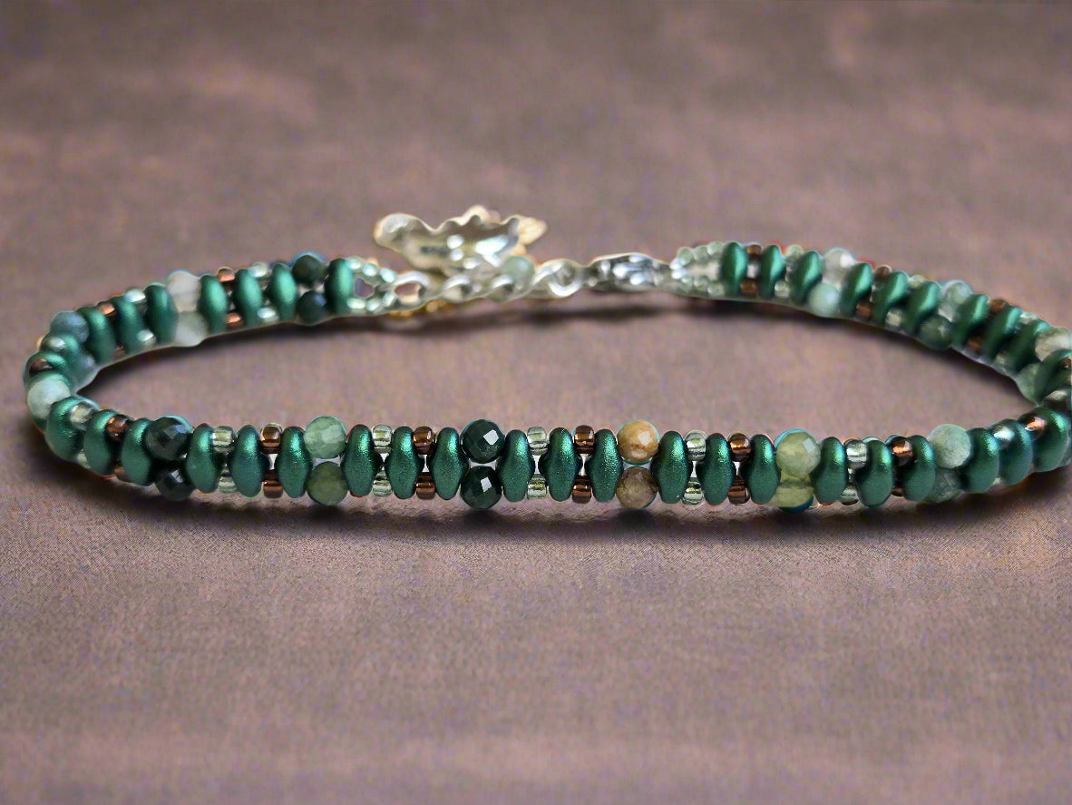 Beaded bracelet with green and brown stones on a light wooden surface