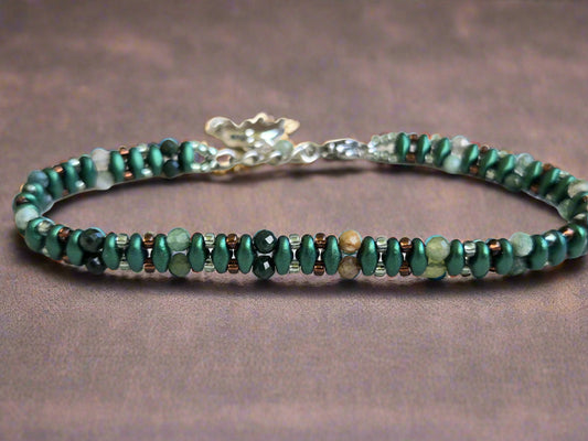 Beaded bracelet with green and brown stones on a light wooden surface