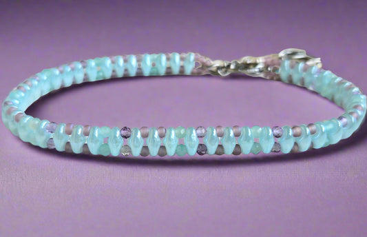 Beaded bracelet with alternating light blue and purple beads on a wooden surface