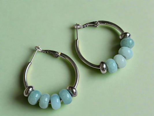 Silver hoop earrings with turquoise beads on a wooden surface