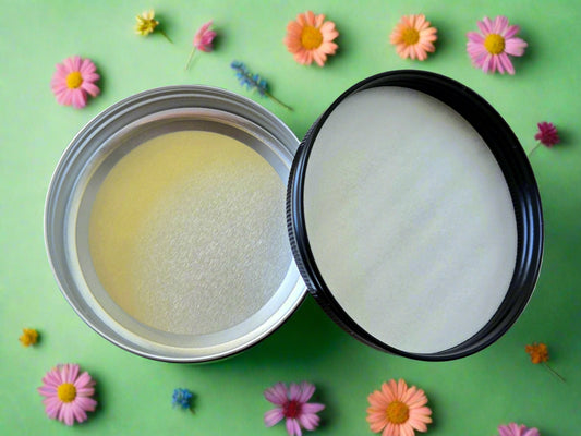 Two containers of cream, one open and one closed, on a wooden surface.