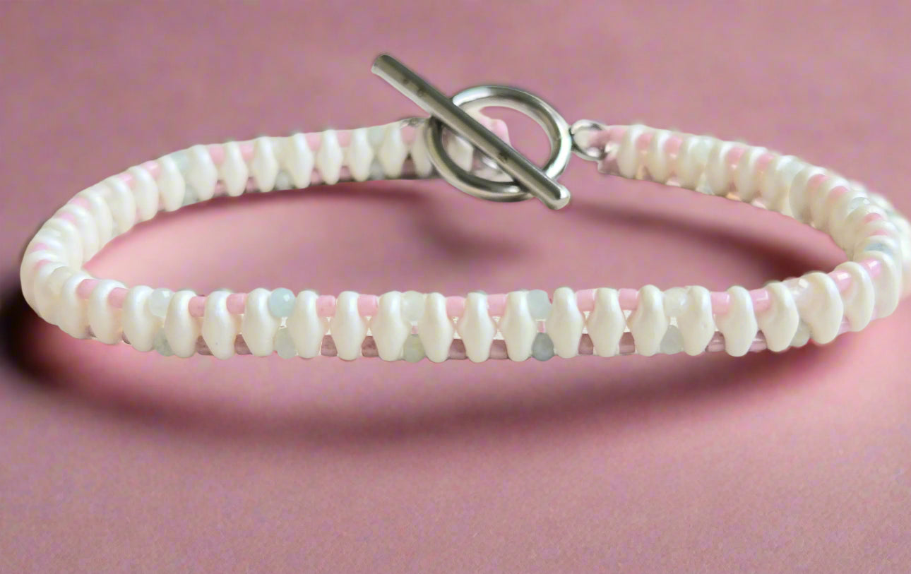 Bracelet with pink and white beads on a light wooden surface