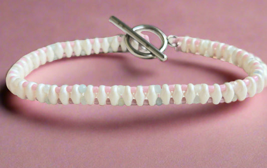 Bracelet with pink and white beads on a light wooden surface