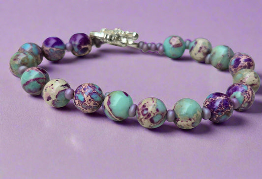 Beaded bracelet with purple and blue marbled beads on a light wooden surface