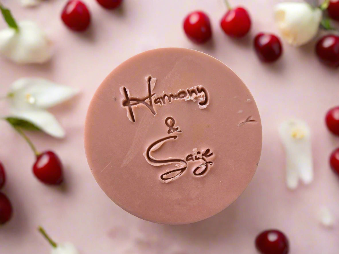 Round pink soap with 'Harmony & Sage' branding on a wooden surface